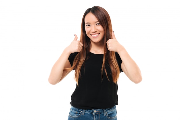 Ritratto del primo piano di giovane donna asiatica felice che mostra pollice sul gesto