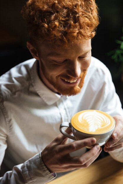 Ritratto del primo piano di giovane tazza di caffè bella della tenuta del tipo della testarossa