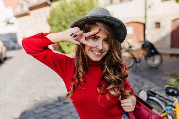 Ritratto del primo piano di invitare la donna dagli occhi azzurri con il manicure nero sorridente felice sul fondo della strada