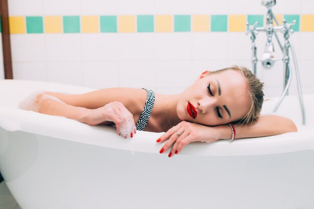 Ritratto del primo piano di una giovane donna che si distende nella vasca da bagno