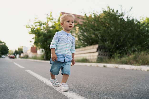 Ritratto del ragazzino sveglio che cammina sulla strada nel suo quartiere