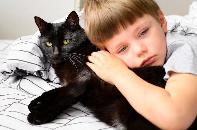 Ritratto del ragazzo adorabile che abbraccia il suo gatto