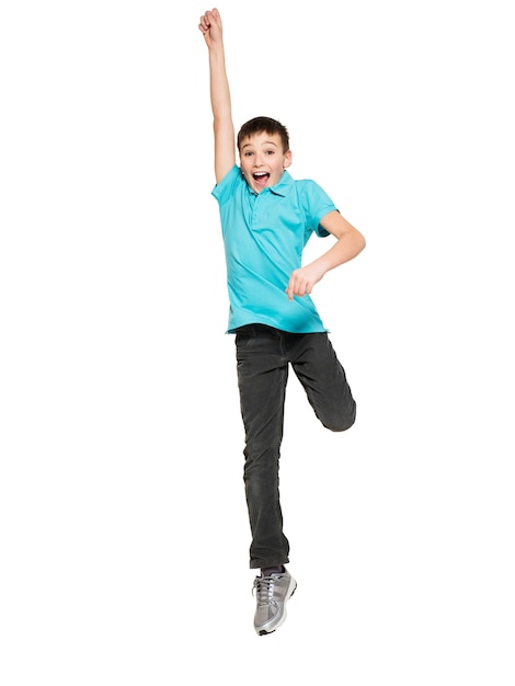 Ritratto del ragazzo teenager felice di risata che salta con le mani alzate in su - isolato su bianco