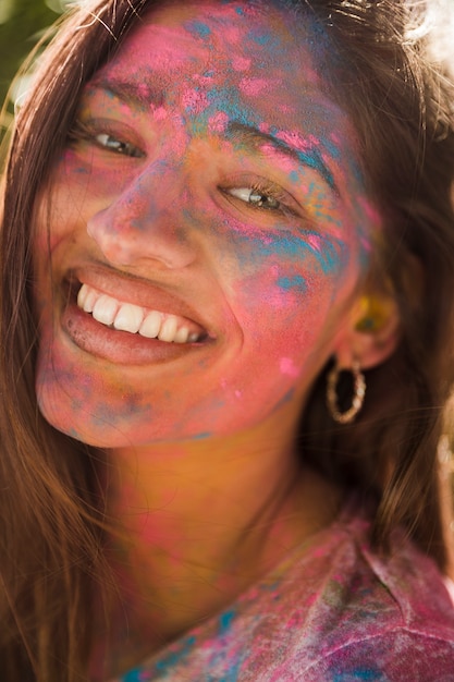 Ritratto del volto di una donna sorridente coperto con colori holi