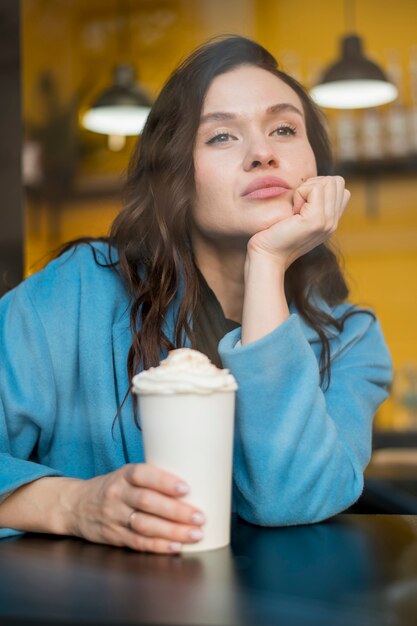 Ritratto dell'adolescente che posa con la cioccolata calda