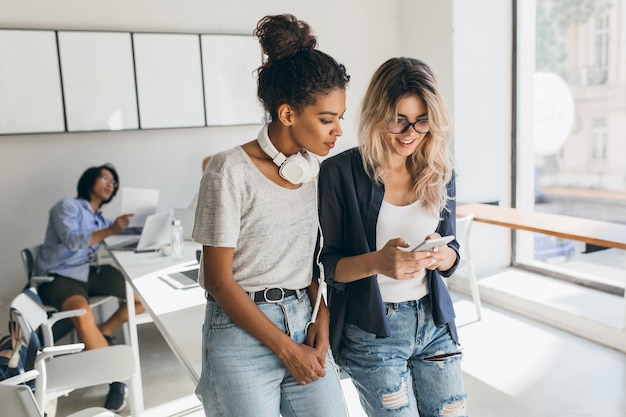 Ritratto dell'interno del programmatore asiatico con donne africane e bianche. Studenti internazionali che si preparano per gli esami nell'auditorium dell'università e utilizzano i computer.