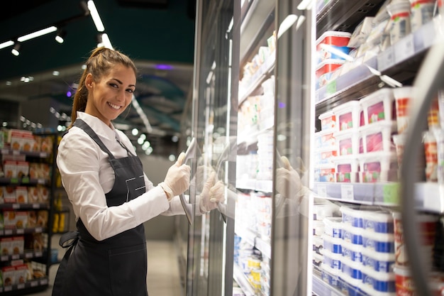 Ritratto dell'operaio del supermercato che fa una pausa il congelatore con il cibo