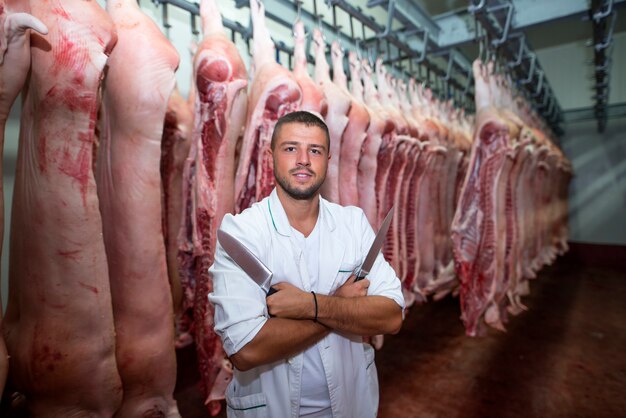 Ritratto dell'operaio professionale dell'industria in vestito bianco che tiene paio di coltelli