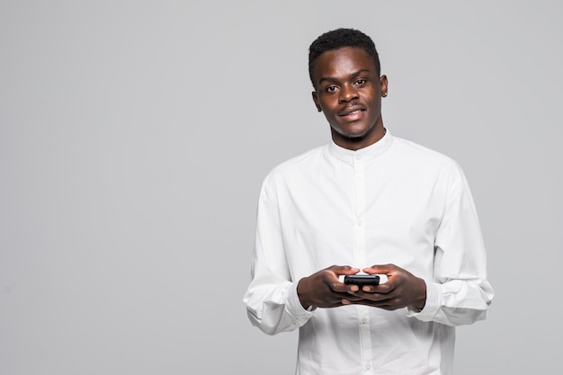 Ritratto dell'uomo afro bello che invia e che ottiene i messaggi al suo amante isolato su fondo grigio