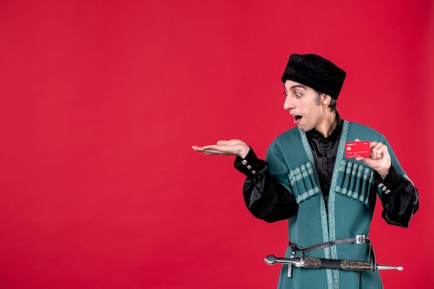 Ritratto dell'uomo azero in costume tradizionale che tiene la carta di credito su novruz etnico della molla rossa