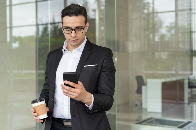 Ritratto dell&#39;uomo d&#39;affari concentrato che legge messaggio mobile