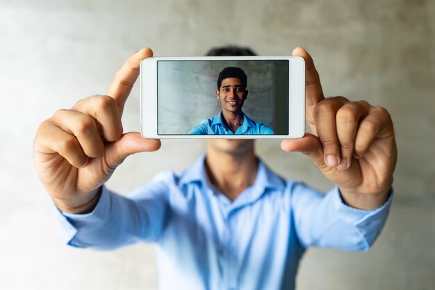 Ritratto dell&#39;uomo d&#39;affari sorridente che prende selfie con lo smartphone.