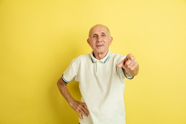 Ritratto dell'uomo maggiore caucasico isolato su studio giallo