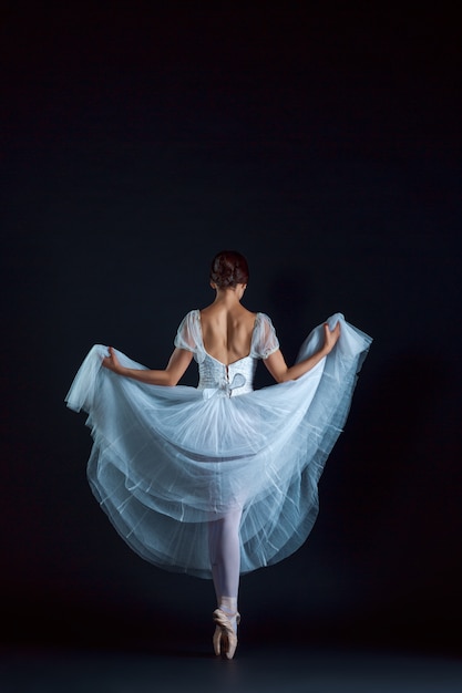 Ritratto della ballerina classica in abito bianco sul muro nero