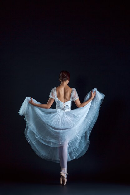 Ritratto della ballerina classica in abito bianco sul muro nero