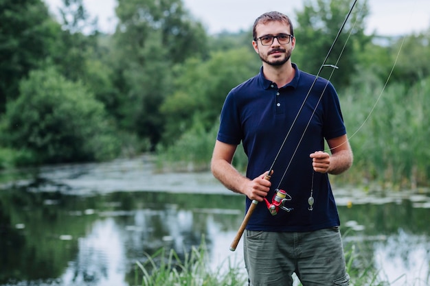 Ritratto della canna da pesca sorridente della tenuta dell&#39;uomo vicino al lago