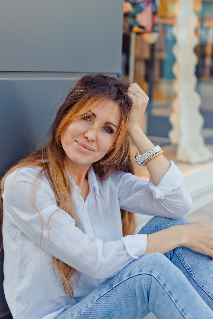Foto gratuito ritratto della donna adorabile che si siede sulla terra che sorride alla via durante il giorno.