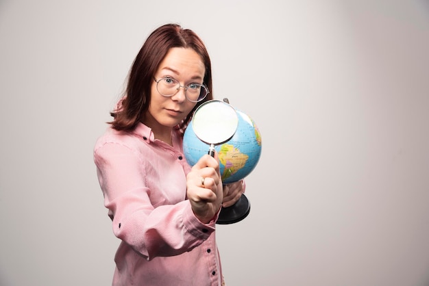 Ritratto della donna che tiene una lente d'ingrandimento e un globo terrestre. Foto di alta qualità