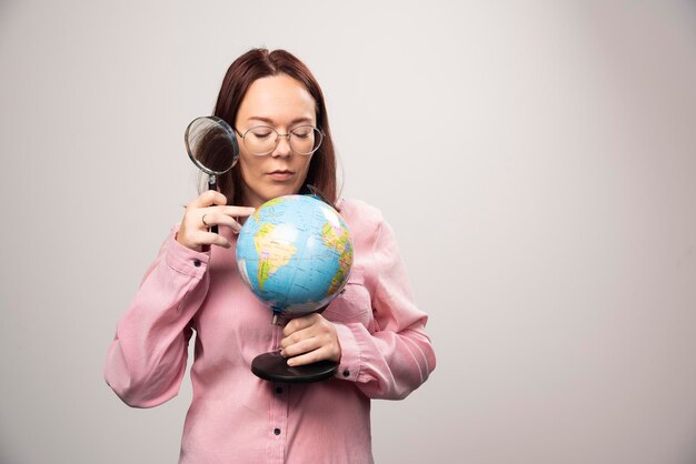 Ritratto della donna che tiene una lente d'ingrandimento e un globo terrestre. Foto di alta qualità