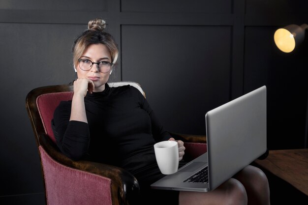 Ritratto della donna di affari adulta che mangia caffè all'ufficio