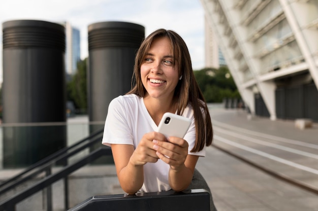 Ritratto della donna di smiley che propone mentre tiene il suo telefono