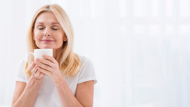 Ritratto della donna matura che gode di una tazza di caffè