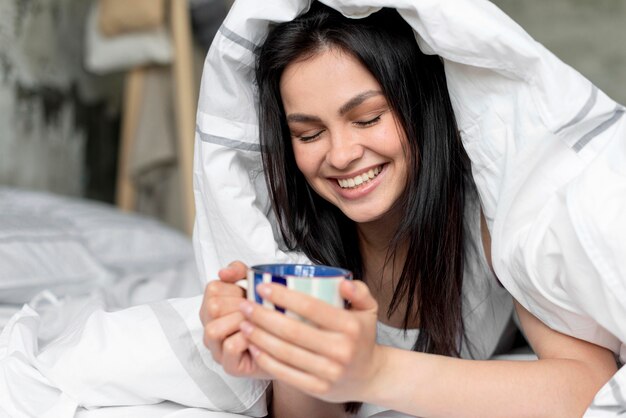 Ritratto della donna positiva che tiene tazza