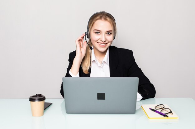 Ritratto della donna sorridente con l'operatore del servizio d'assistenza del computer portatile con le cuffie all'ufficio