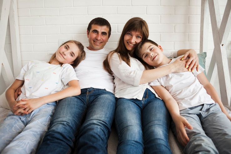 Foto gratuito ritratto della famiglia amorosa che si trova sul letto che esamina macchina fotografica in camera da letto