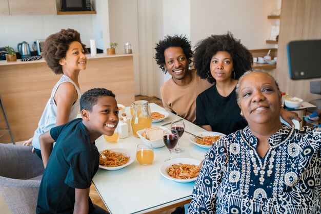 Ritratto della famiglia multigenerazionale afroamericana che prende un selfie insieme al telefono cellulare mentre cenando a casa. Concetto di famiglia e stile di vita.