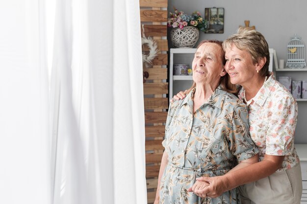 Ritratto della figlia matura con sua madre senior a casa