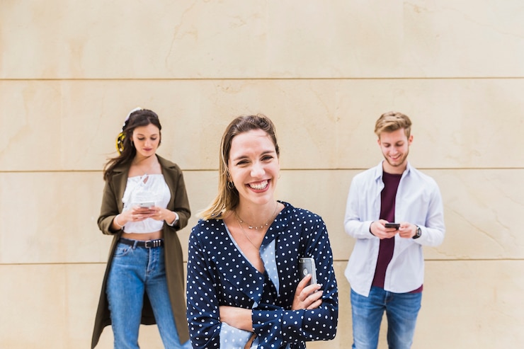 Foto gratuito ritratto della giovane donna sorridente davanti al maschio e alla femmina che per mezzo del cellulare