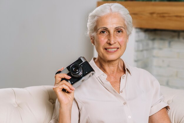 Ritratto della macchina fotografica senior sorridente della tenuta della donna a disposizione