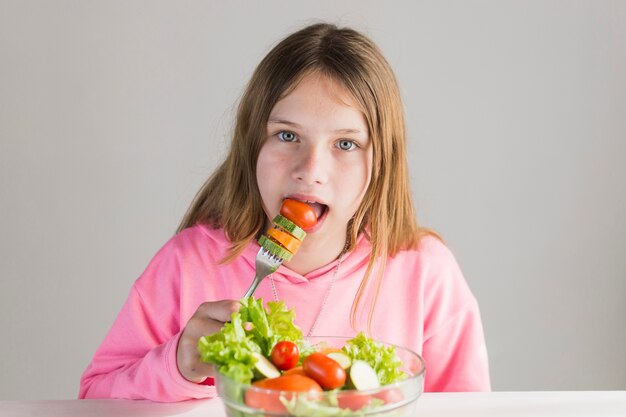 Ritratto della ragazza che mangia insalata sana con la forcella