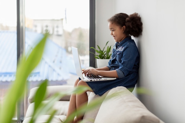 Ritratto della ragazza che per mezzo del computer portatile