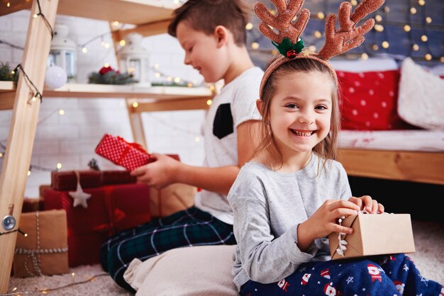 Ritratto della ragazza felice che apre il regalo di Natale