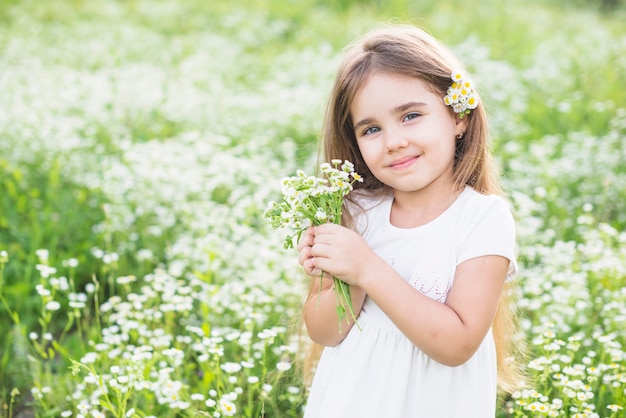 Ritratto della ragazza felice che tiene i fiori bianchi in sua mano