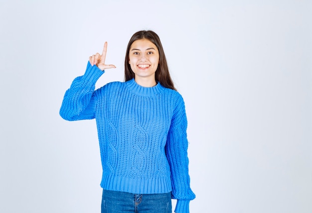 Ritratto della ragazza sorridente che indica su bianco.