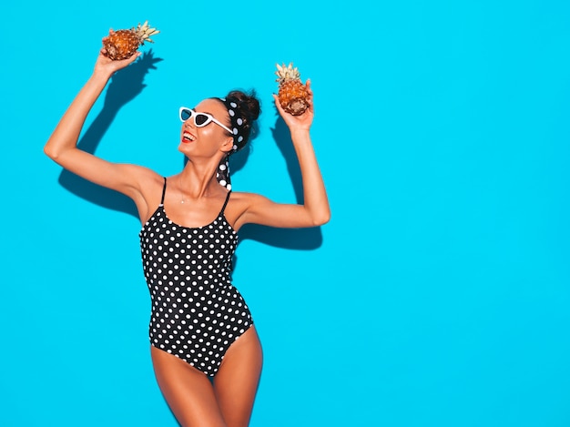 Ritratto della ragazza sorridente del brunette in costume da bagno ed occhiali da sole dello swimwear dei piselli di estate.