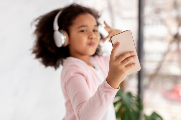 Ritratto della ragazza sveglia che prende un selfie mentre ascoltando la musica