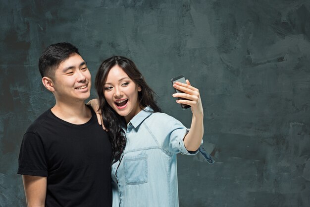 Ritratto delle coppie coreane sorridenti su una parete grigia