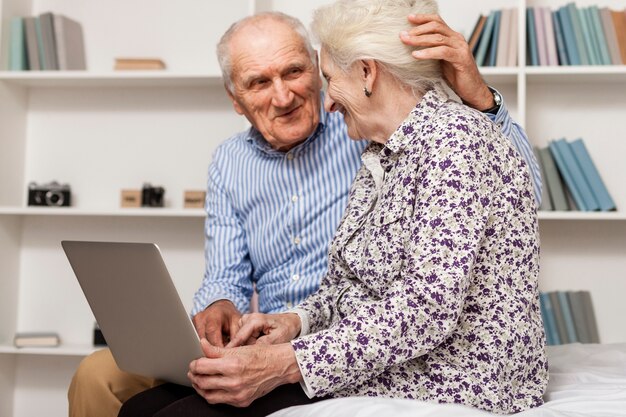 Ritratto delle coppie senior che per mezzo di un computer portatile