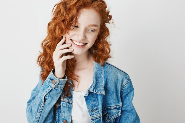 Ritratto dello sguardo sorridente della ragazza timida sveglia della testarossa nel lato. Copia spazio.