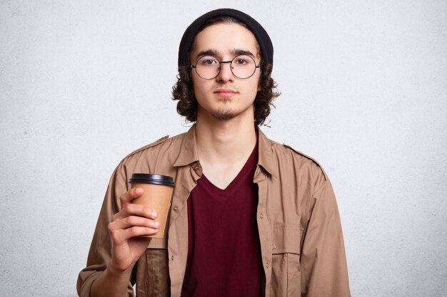 Ritratto dello studio dell'uomo serio con la tazza di caffè aromatico caldo.