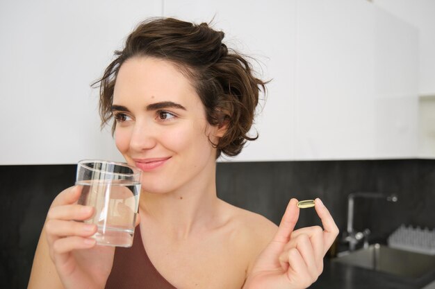 Ritratto di acqua potabile sportiva che assume integratori dietetici vitaminici per una pelle sana con om