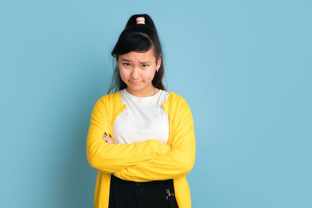 Ritratto di adolescente asiatico isolato su sfondo blu studio