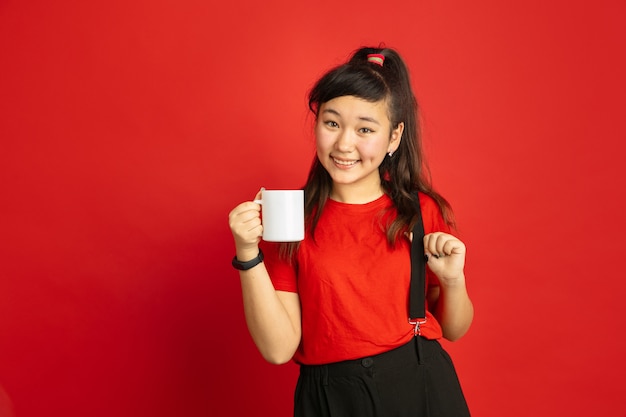 Ritratto di adolescente asiatico isolato su sfondo rosso studio