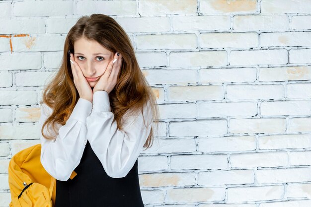 Ritratto di adorabile studente che tiene la mano sul viso Foto di alta qualità