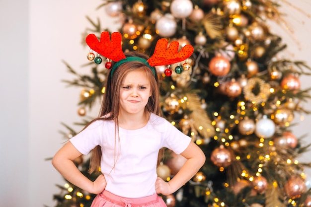 Ritratto di bambina che indossa cervi natale cappello vacanze invernali e concetto di persone