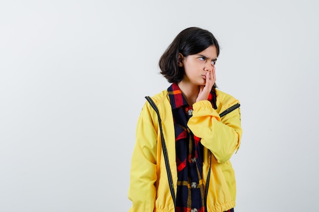 Ritratto di bambina tenendo la mano sulla bocca in camicia a quadri, giacca e guardando premurosa vista frontale